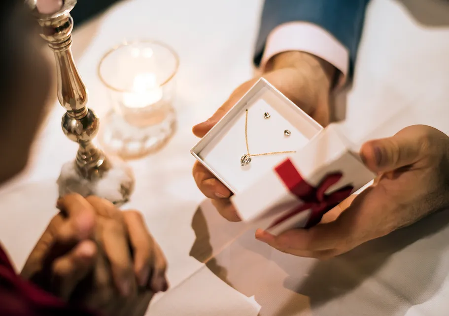 Joven regalando una cadena y aretes de oro dentro de una caja.